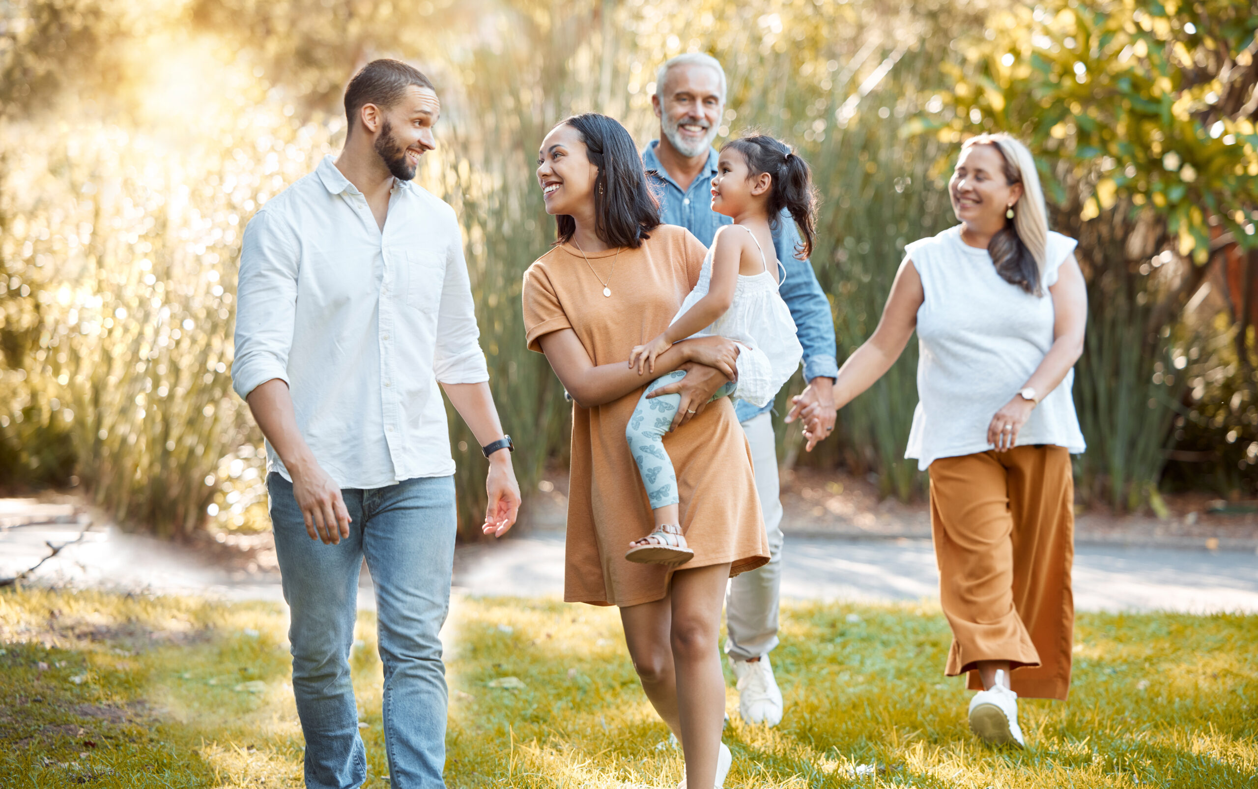 A family of three generations walking together outdoors in the evening light
