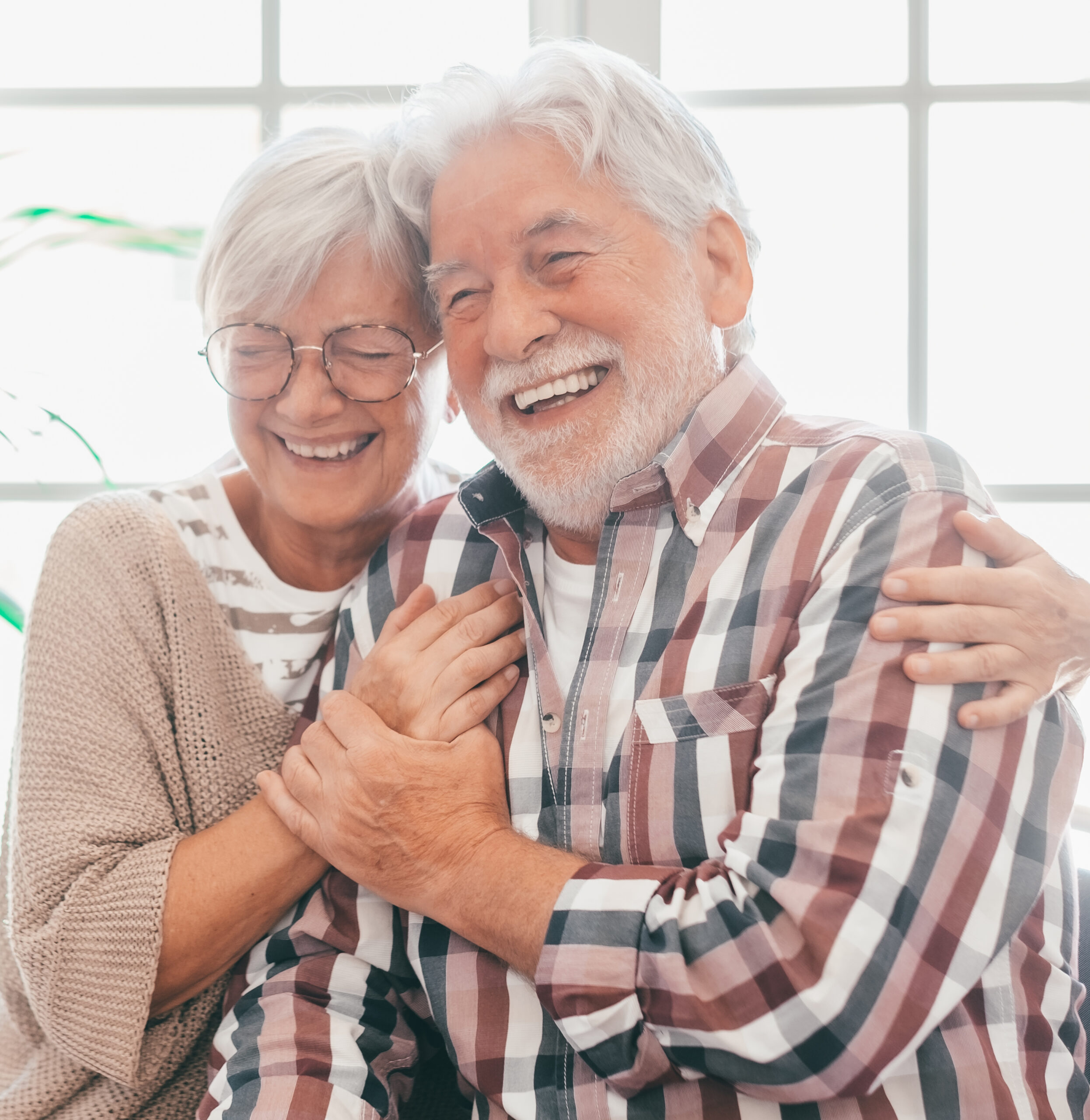 An older couple smiling and holding each other at home